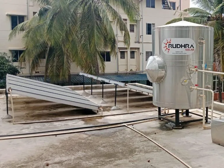 Rudhra Solar commercial water heater with a vertical stainless steel tank and flat plate collectors at an institutional campus